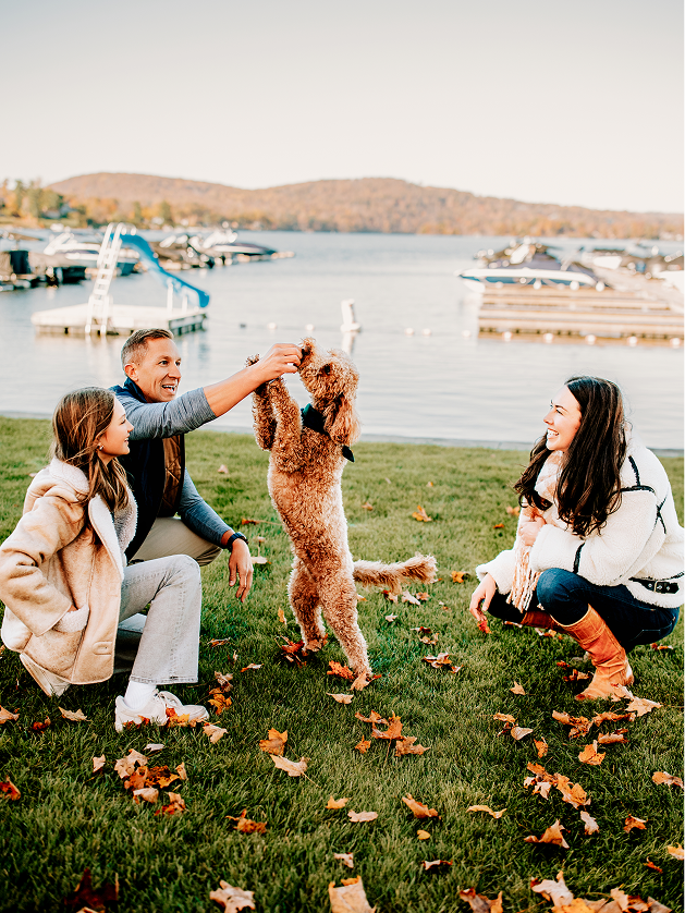Family playing with dog by the lake